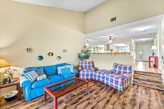 living room featuring wood-type flooring, a textured ceiling, and ceiling fan