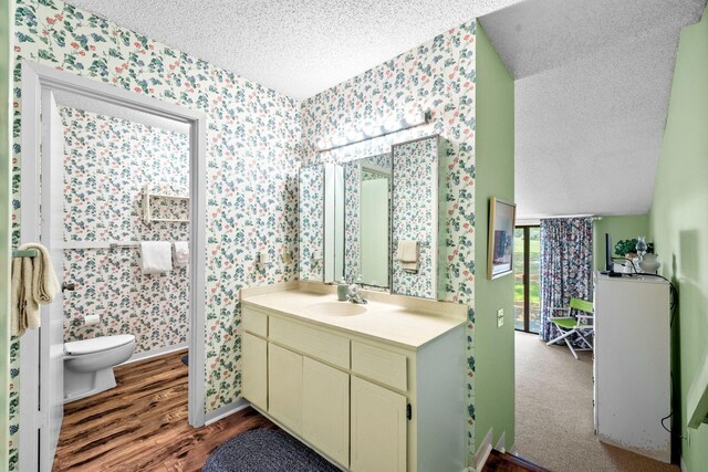 bathroom featuring vanity, toilet, wood-type flooring, and a textured ceiling