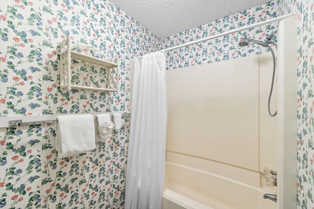 bathroom featuring shower / bath combination with curtain and a textured ceiling