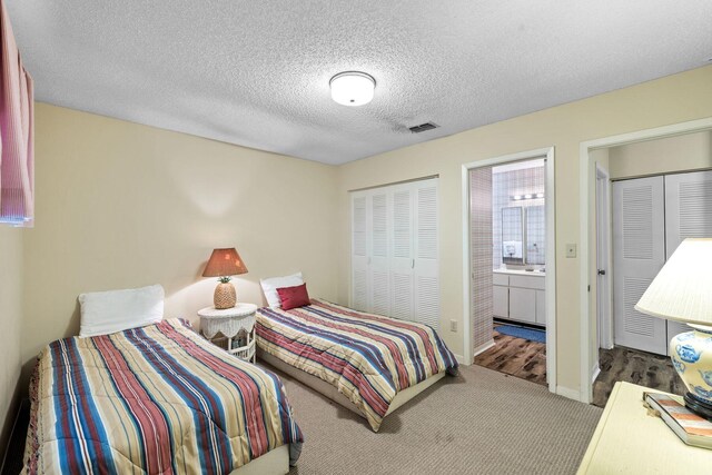 bedroom with carpet, a textured ceiling, and ensuite bath