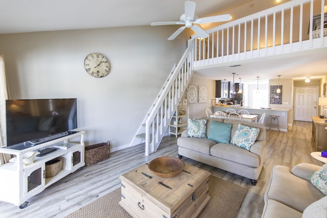 living room featuring ceiling fan, a towering ceiling, and light wood-type flooring