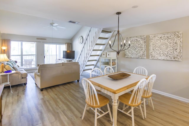 dining space with ceiling fan with notable chandelier, light hardwood / wood-style flooring, and lofted ceiling