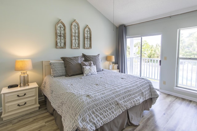 bedroom with access to outside, multiple windows, lofted ceiling, and light hardwood / wood-style floors