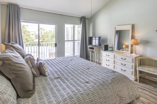 bedroom featuring access to exterior, light hardwood / wood-style floors, and vaulted ceiling