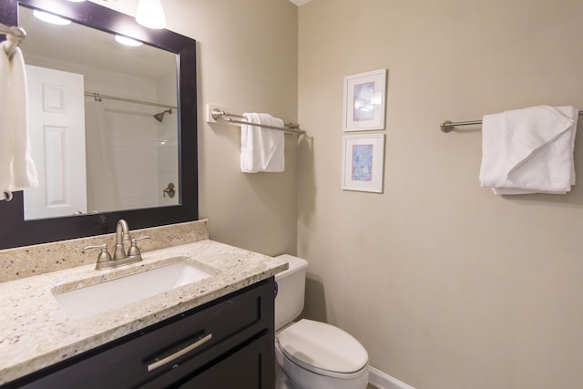 bathroom with tiled shower, vanity, and toilet