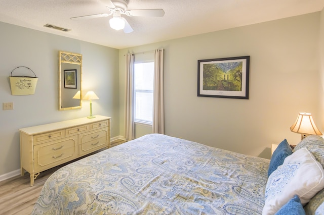 bedroom featuring ceiling fan, a textured ceiling, and light wood-type flooring