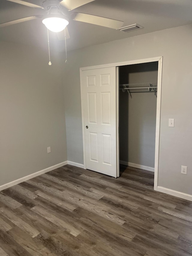 unfurnished bedroom featuring ceiling fan, dark wood-type flooring, and a closet