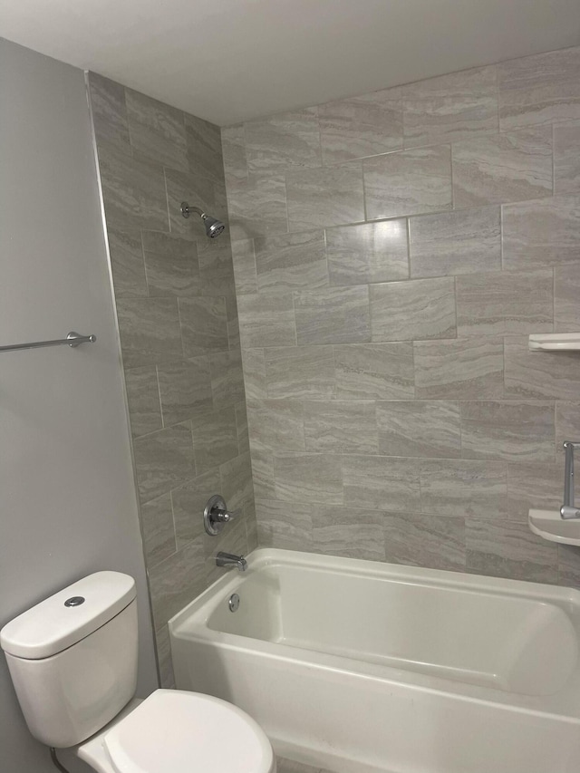 bathroom featuring tiled shower / bath combo and toilet