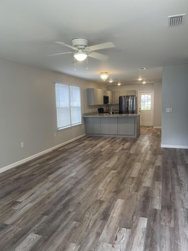 kitchen with sink, dark wood-type flooring, kitchen peninsula, stainless steel fridge, and gray cabinets