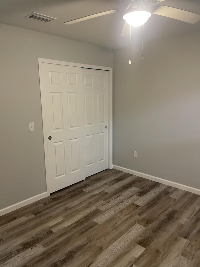 unfurnished bedroom featuring ceiling fan, a closet, and dark hardwood / wood-style floors