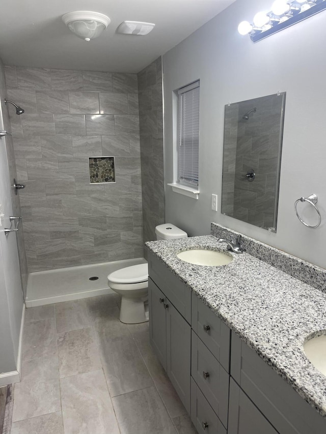 bathroom with tiled shower, vanity, and toilet