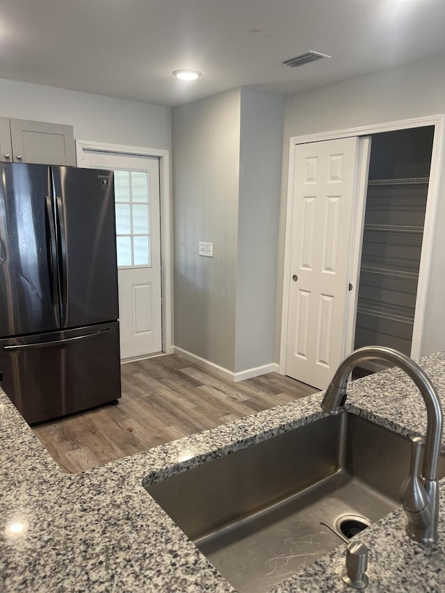 kitchen featuring stone counters, stainless steel refrigerator, and sink