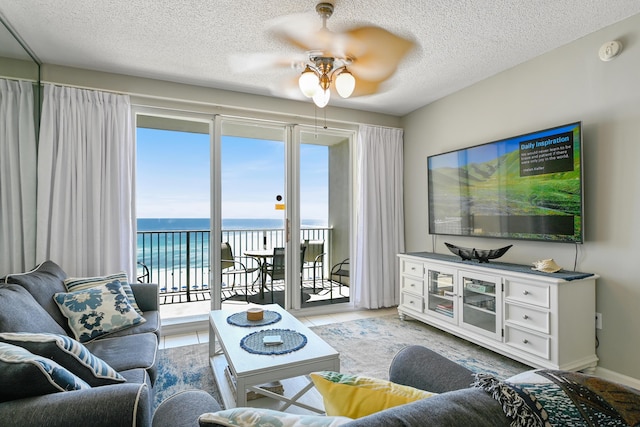 living area featuring a ceiling fan, a textured ceiling, baseboards, and light tile patterned floors