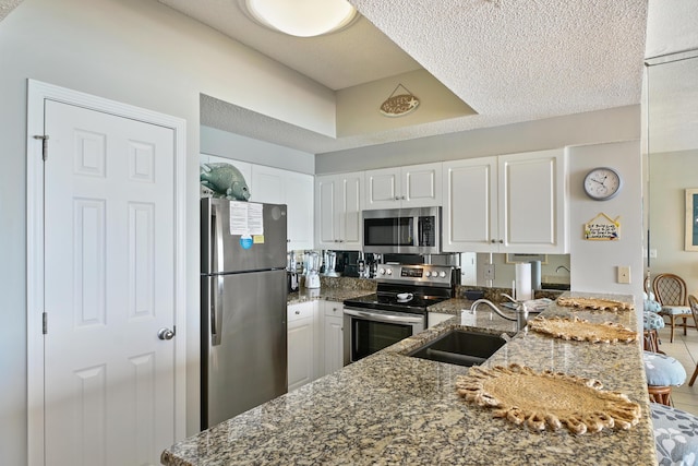 kitchen featuring dark stone countertops, white cabinetry, stainless steel appliances, and a sink