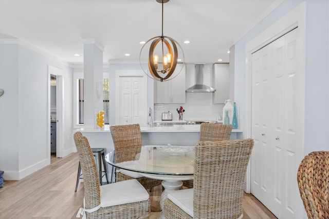 dining space featuring an inviting chandelier, light hardwood / wood-style floors, and crown molding