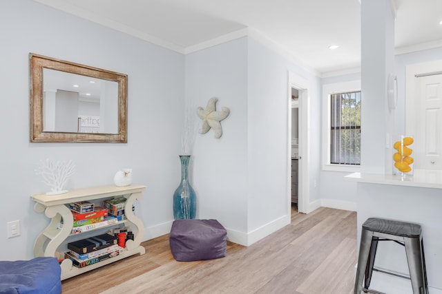 sitting room with ornamental molding and light hardwood / wood-style flooring