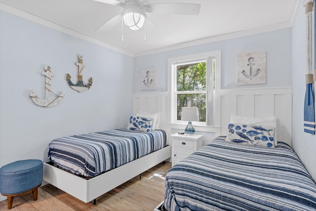 bedroom featuring wood-type flooring, ornamental molding, and ceiling fan