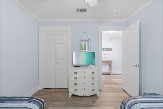 bedroom featuring ceiling fan, a closet, light hardwood / wood-style flooring, and ornamental molding