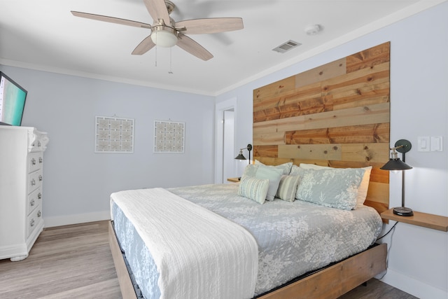 bedroom with crown molding, wood-type flooring, and ceiling fan