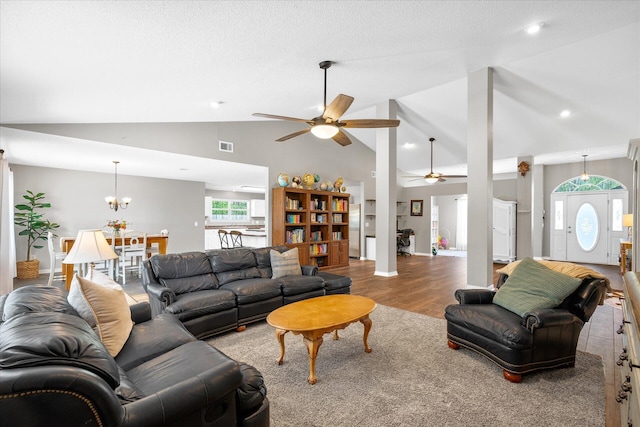 living room with hardwood / wood-style floors, ceiling fan with notable chandelier, and high vaulted ceiling