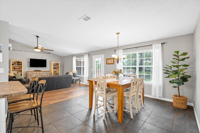 dining space featuring a textured ceiling, ceiling fan with notable chandelier, dark wood-type flooring, and lofted ceiling