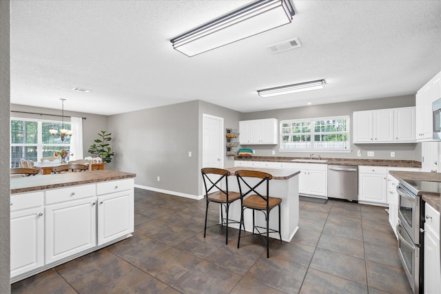 kitchen with appliances with stainless steel finishes, a center island, white cabinetry, and plenty of natural light