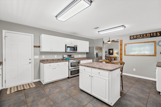 kitchen with white cabinets, appliances with stainless steel finishes, a kitchen island, and a breakfast bar area