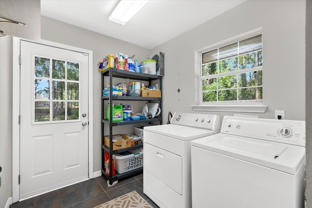 washroom featuring plenty of natural light, dark tile patterned floors, a textured ceiling, and washing machine and clothes dryer