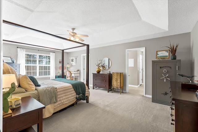 bedroom with a raised ceiling, ceiling fan, light colored carpet, and a textured ceiling