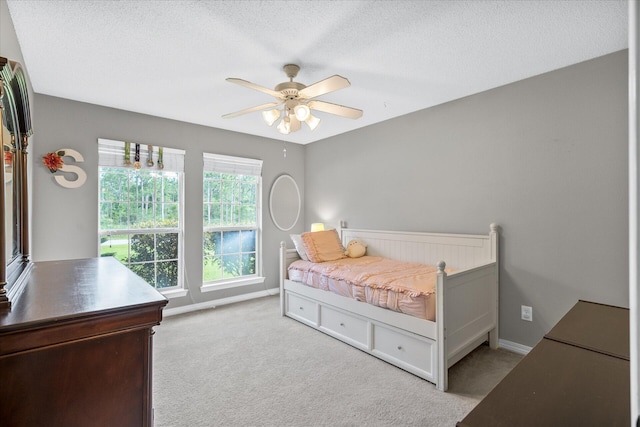 bedroom featuring light carpet, a textured ceiling, and ceiling fan