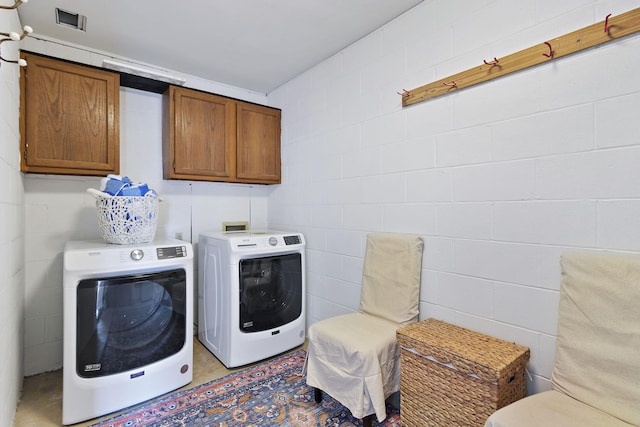 clothes washing area with cabinets and washing machine and clothes dryer