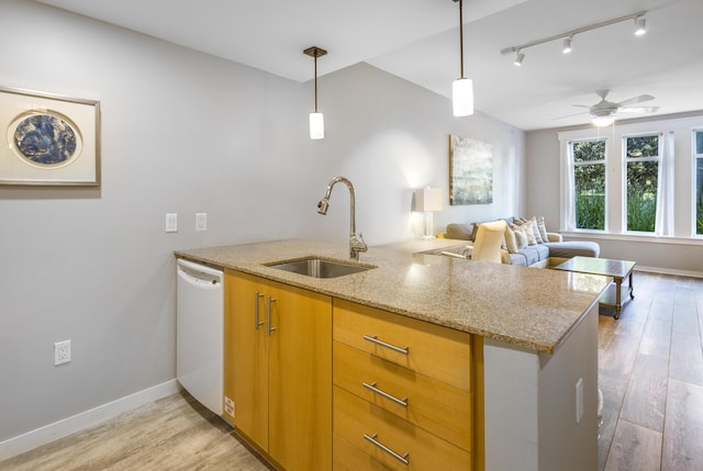 kitchen featuring dishwasher, sink, light stone counters, and kitchen peninsula