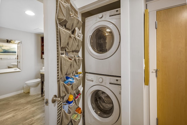 clothes washing area featuring stacked washer / dryer and light wood-type flooring