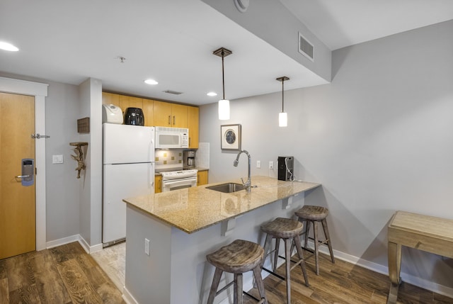 kitchen featuring sink, light brown cabinets, kitchen peninsula, pendant lighting, and white appliances