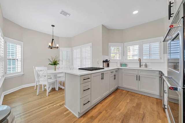 kitchen with sink, light hardwood / wood-style floors, and kitchen peninsula