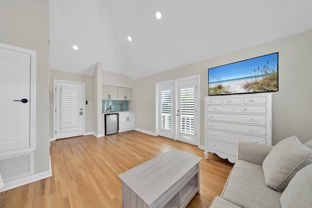 living room with high vaulted ceiling and light hardwood / wood-style flooring