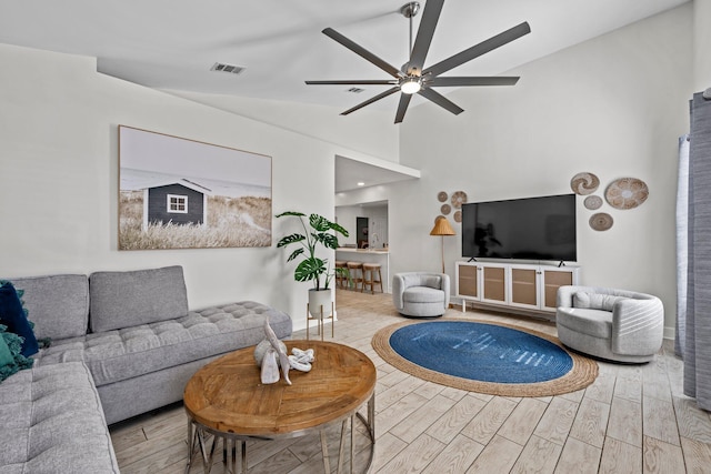 living room featuring ceiling fan, vaulted ceiling, and light hardwood / wood-style flooring