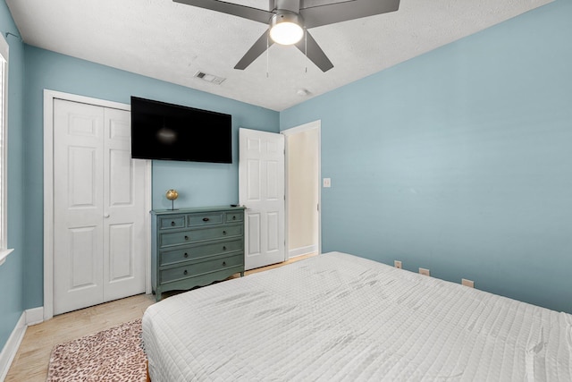 bedroom with ceiling fan, light wood-type flooring, a textured ceiling, and a closet