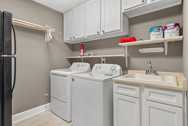 laundry room with separate washer and dryer, cabinets, sink, and light hardwood / wood-style floors