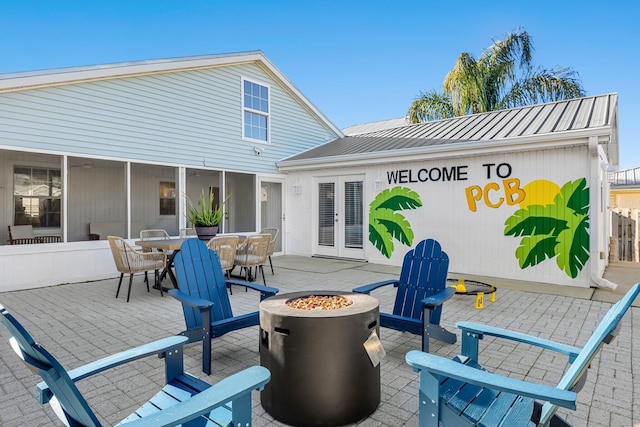 back of property with a fire pit, a patio, and french doors