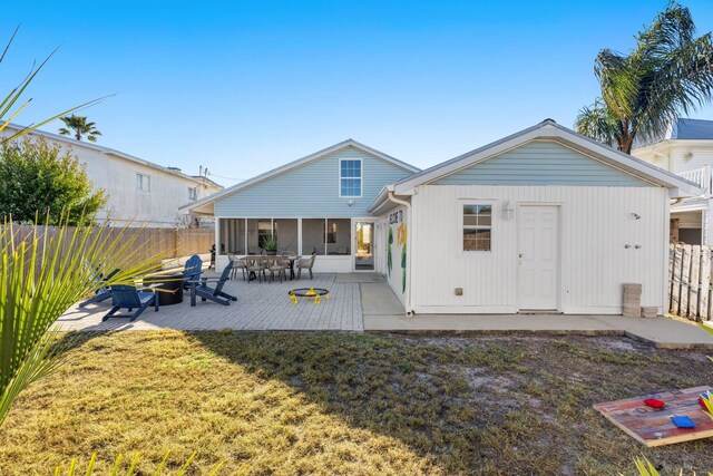 rear view of property with a sunroom, a patio area, and a lawn