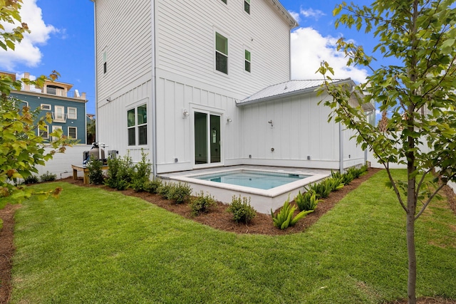 rear view of property featuring a lawn and a jacuzzi