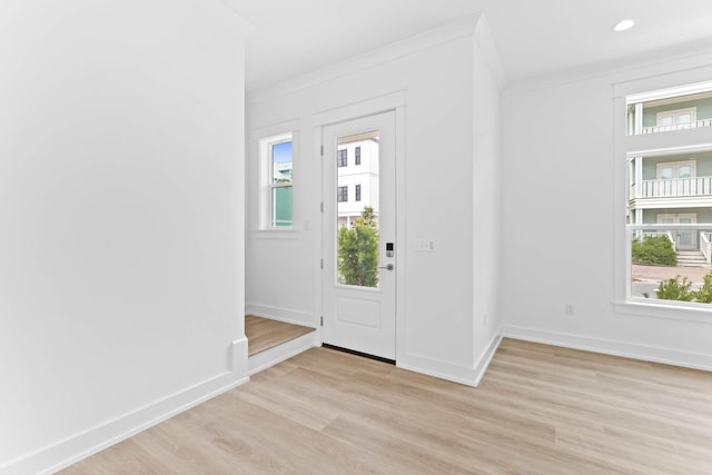 entrance foyer with light hardwood / wood-style floors, a wealth of natural light, and ornamental molding