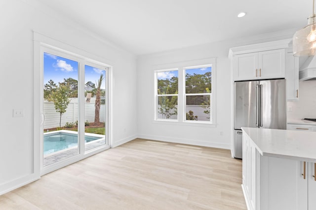 kitchen featuring backsplash, white cabinets, hanging light fixtures, light wood-type flooring, and high quality fridge