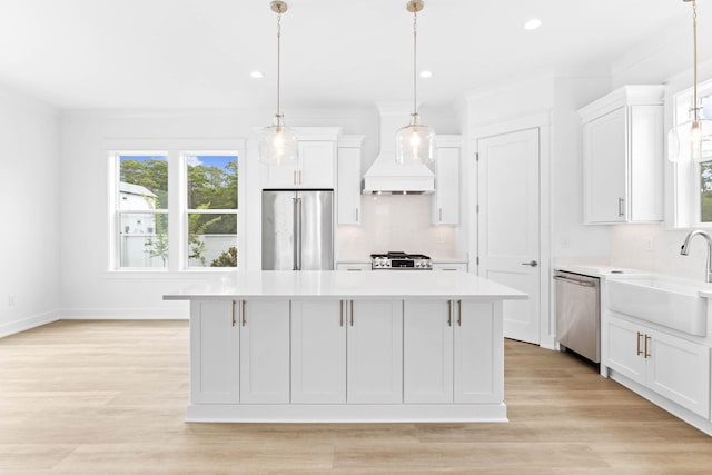 kitchen with white cabinets, appliances with stainless steel finishes, a center island, and pendant lighting