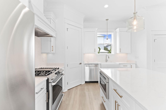 kitchen with sink, light stone countertops, decorative light fixtures, white cabinetry, and stainless steel appliances