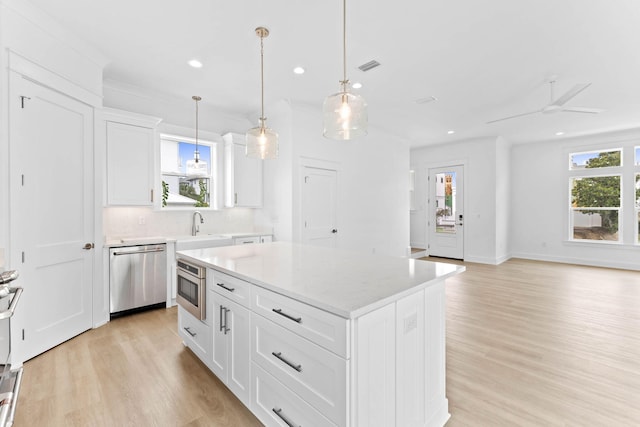 kitchen featuring stainless steel dishwasher, ceiling fan, decorative light fixtures, white cabinets, and a center island