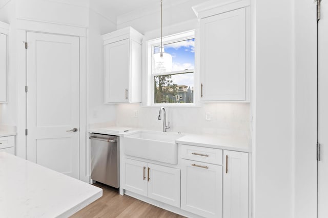 kitchen with sink, stainless steel dishwasher, decorative light fixtures, white cabinets, and light wood-type flooring