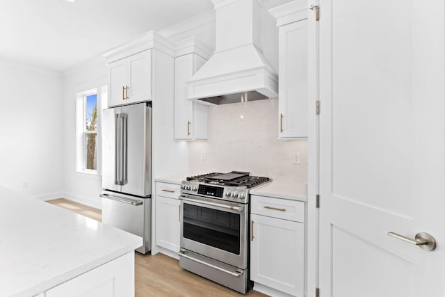 kitchen featuring light hardwood / wood-style flooring, white cabinetry, premium range hood, and stainless steel appliances