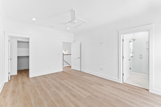 unfurnished bedroom featuring ensuite bath, a spacious closet, ceiling fan, a closet, and light wood-type flooring